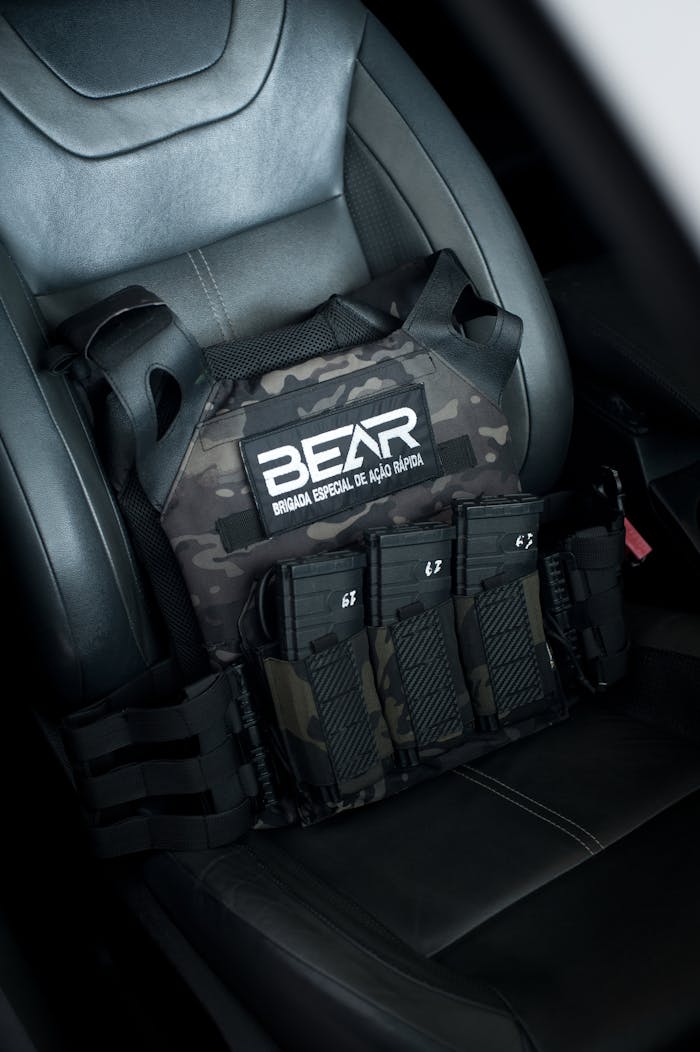 A tactical vest with magazines sits on a car seat, featuring camouflage design and text logo.